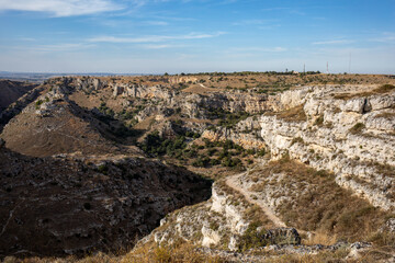 Fototapeta na wymiar View of Gravina river canyon and park of the Rupestrian Churches of Matera with houses in caves di Murgia Timone near ancient town Matera (Sassi), , Basilicata, Italy