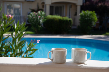 Two cups of coffee near swimming pool. Summer cozy morning in luxury villa terras with swimming pool.