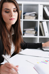 Female hand holding silver pen ready to make note in opened notebook sheet. Businesswoman in suit...