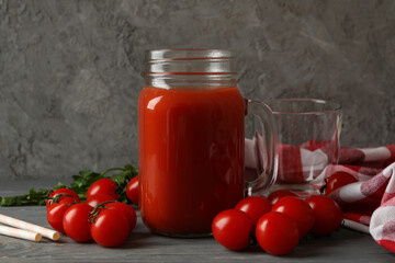 Jar of tomato juice, tomatoes and kitchen towel on wooden background