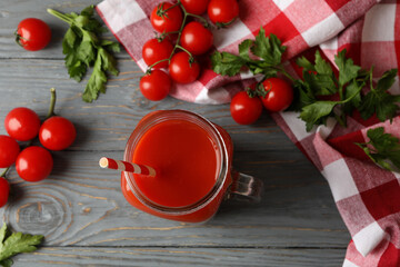 Jar of tomato juice, tomatoes and kitchen towel on wooden background