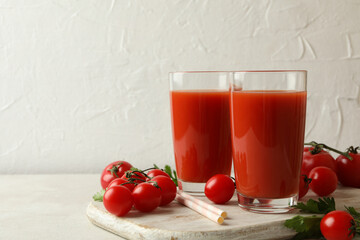 Board with tomato juice and tomatoes on white textured background