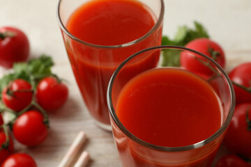 Board with glasses of tomato juice and tomatoes, close up