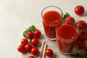 Board with tomato juice and tomatoes on white textured background