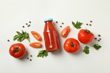Bottle of tomato juice, tomatoes and spices on white background