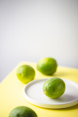 Fresh lime on plite over two tone background, yellow and white, minimalist composition