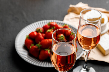 Plate with fresh strawberry and glass of wine on black background