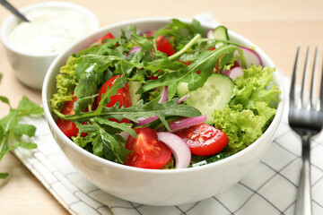 Delicious salad with arugula and vegetables on table, closeup