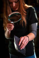  young woman looking into an empty wallet with magnifying glass ,cost of living household finance ,