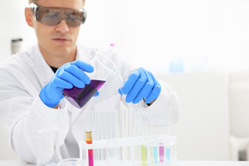 A male chemist holds test tube of glass in his hand overflows a liquid solution of potassium...