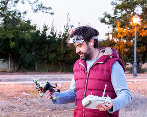 Young boy happily looks at the drone in his hand and the station in the other hand. He wears drone...