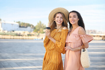 Beautiful young women in stylish dresses on city street