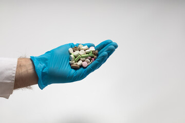 A hand in a glove holds a handful of pills
