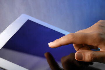 Woman working with modern tablet on dark background, closeup
