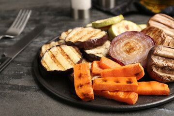 Delicious grilled vegetables and mushrooms served on grey table, closeup