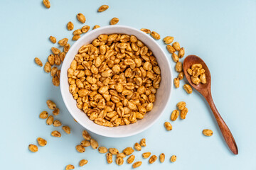 Dry breakfast air caramel wheat in a deep bowl on a blue background, top view