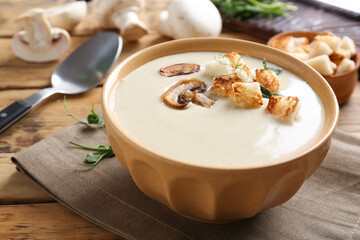 Delicious cream soup with mushrooms on wooden table, closeup