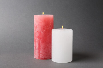 Stylish color burning candles on grey background