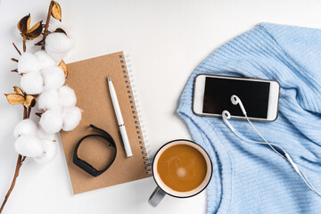 A modern creative background of a sweater, a cup of coffee, a smartphone and a branch of cotton. Cozy home working environment