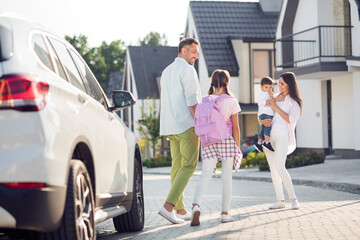 Photo portrait of father bringing daughter back from school to mother and brother outdoors in summer on street