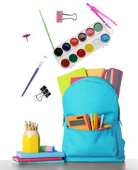 School stationery flying over backpack on white background