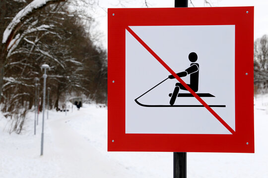 Warning sign forbidding sledding in the snowy park. Children safety during winter holidays