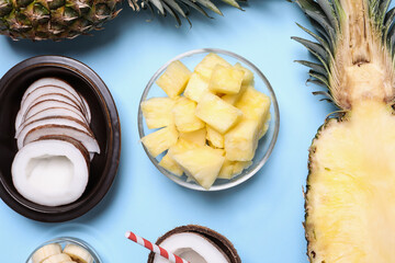 Flat lay composition with pineapples and coconuts on light blue background