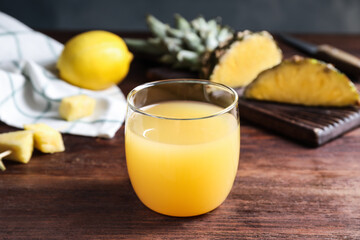 Fresh pineapple juice in glass on wooden table