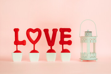 The red love word that stands on the stand with heart shape and lantern on pink background