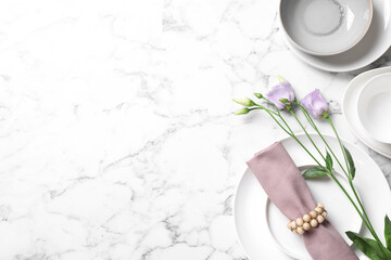 Flat lay composition with beautiful dishware and flowers on white marble table. Space for text