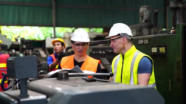 Staff or technicians are checking the operation of the old machine via the tablet.