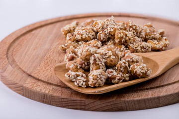 Cashew nuts in sesame seeds with honey on a wooden spoon.