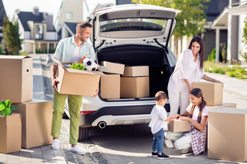 Full size photo of happy smiling cheerful family moving to new house mom dad pack stuff in car...
