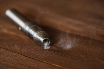 Electronic cigarette on a wooden table. Smoke.