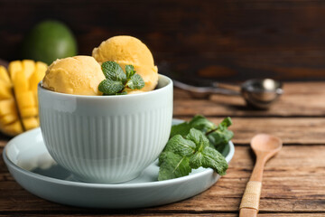 Delicious mango ice cream served on wooden table, space for text