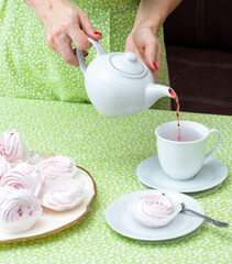 Pour tea from the teapot into a cup for a pleasant pastime. Selective focus.