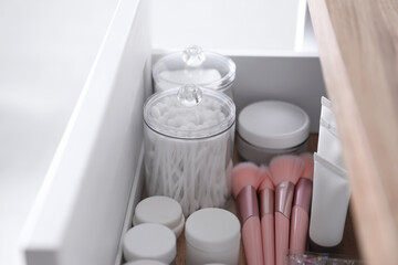 Cotton buds, pads, creams and makeup brushes in open drawer