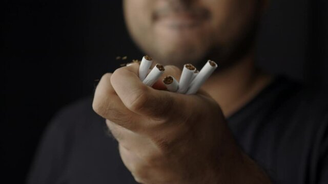A young man crushed cigarettes with his hand. Because he wants to quit smoking. World No Tobacco Day.