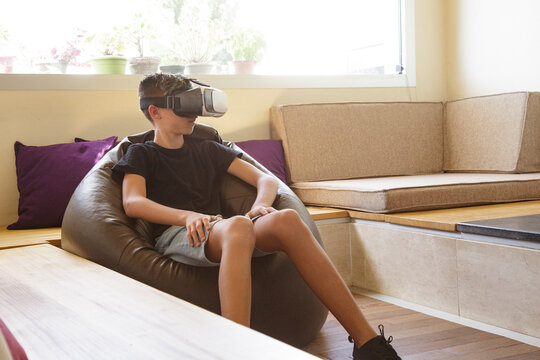 ragazzo adolescente gioca con la tecnologia virtuale grazie ad un visore nel salotto di casa