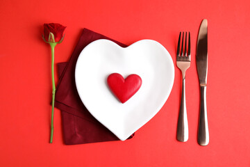 Elegant table setting for romantic dinner on red background, flat lay. Valentine's day celebration