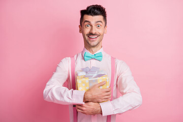 Photo portrait of excited amazed guy hugging gift box isolated on pastel pink colored background