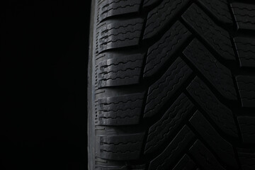 Winter tire on black background, closeup. Car maintenance