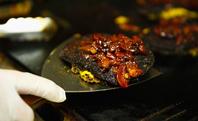 Black pudding steak frying on hot pan in fast food restaurant.Chef fries burger meat with spatula in close up