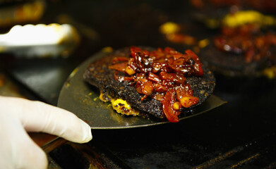 Black pudding steak frying on hot pan in fast food restaurant.Chef fries burger meat with spatula...