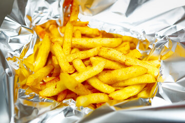 Golden French fries delivered in tinfoil for dinner.Delicious potato chips delivery from fast food...