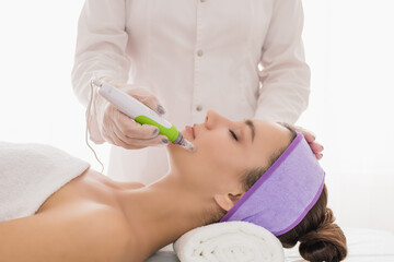Fractional mesotherapy.A young beautiful woman in the cosmetologist’s office receives fractional...