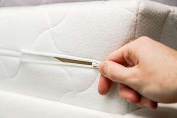 Hand opening cover of new mattress with zipper. Changing and washing cover. Front view. Close up.