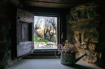 Interior view from the window of a rustic house towards a beautiful garden with trees