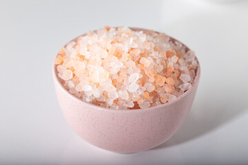 Pink rock salt in a pink bowl on a white background. Himalayan salt in bowl. 