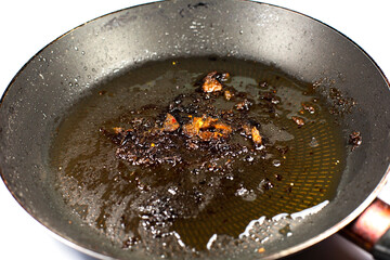 Burnt pan with oil. Fat leftovers close up. Unhealthy food. Damaged kitchenware.